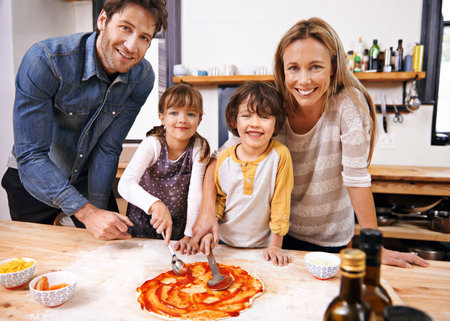 We always make our own pizza. A family making pizza together at home.の写真素材