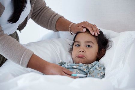 Sick baby in bed with mother hands for child care, support and love. Sad girl at home in winter with...