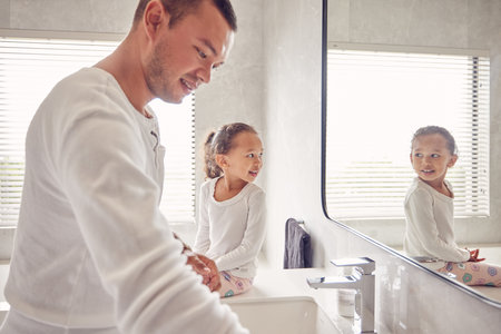 Bathroom, man and child smile in morning before work and school. Cleaning, ready for the day and a father and daughter in a sunny bath room of family home. Happy kid looking at reflection in mirror.の写真素材