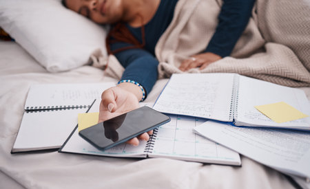 Phone, books and sleeping woman student tired from learning, studying and education exam paper in bed. University or college girl rest with mobile smartphone for online research paperwork documentの写真素材