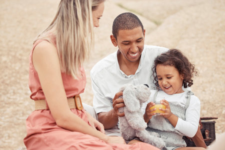 Interracial family, beach travel and summer fun with child enjoying bonding time with mother and father during a picnic on rocks. Happy man and woman playing on vacation or holiday with cute daughterの写真素材