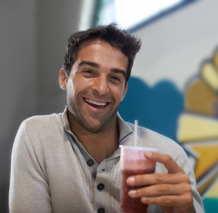 Mmm, refreshing. Portrait of a handsome man drinking a smoothie at a restaurant.の写真素材