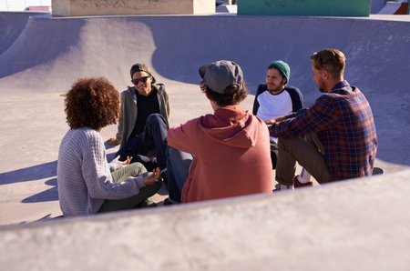 Chilling in the bowl. a group of friends hanging out in the sun at a skate park.の写真素材