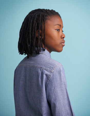 Hes got big dreams for his size. Studio shot of a thoughtful young boy standing against a blue...