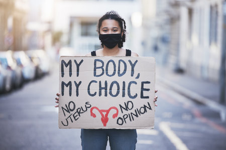Protest woman, abortion choice or healthcare cardboard poster in a city street for body, human rights and law politics. Girl voice, opinion or slogan words for gender equality with face mask portraitの写真素材