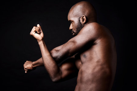 Stretching his superior strength. Studio shot of a muscular african american man stretching his arm muscles.の写真素材