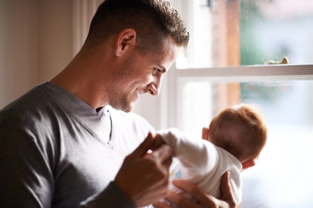 Its a big world out there but youll always be safe with me. a young father standing by a window holding his adorable baby girl.の写真素材