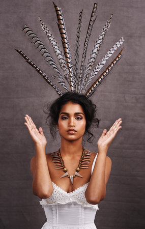 Ruffling feathers. Cropped portrait of a stylish young ethnic woman posing with feathers in a studio.の写真素材