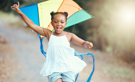 Nature, summer and girl with a kite running in a park with a smile. Weekend, happiness and a little black child having outdoor fun. Freedom, development and growth for happy young kid playing outsideの写真素材