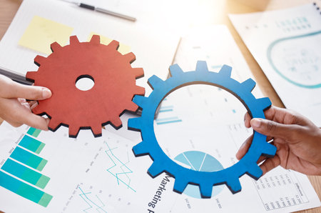 Hand, gear and teamwork with parts in the hands of business people working together as a team for synergy in the office. Collaboration, strategy and marketing with an advertising employee at workの写真素材