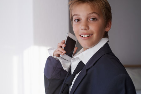Growing up like dad. a young boy wearing his fathers suit and pretending to be a businessman.の写真素材