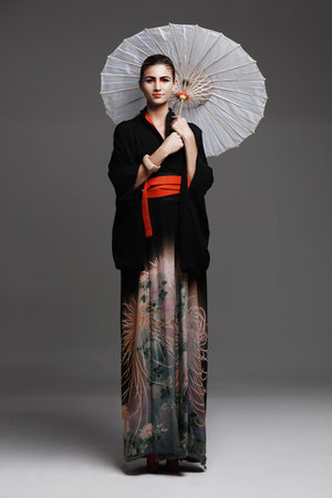 Demure beauty. Studio fashion shot of a young woman wearing oriental-style clothing.の写真素材