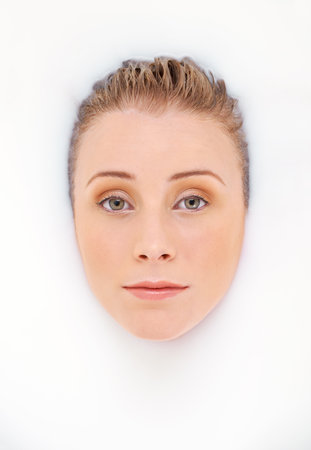A baptism in beauty. Studio shot of an attractive woman indulging in a milky bath.の写真素材