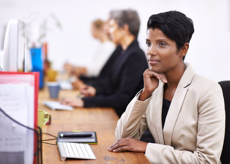 Drifting off on a slow day at the office. an attractive woman sitting at a desk while looking distracted.の写真素材