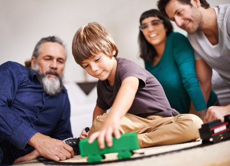 a young child playing with a train set while his family watches.の写真素材