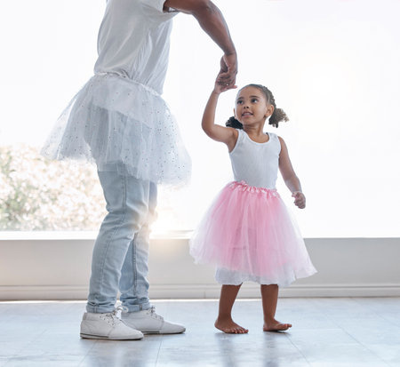 Young girl, learning ballet with dad or teacher for fitness, fun and health at house. Female child dancer in costume dress, dancing with father or dance instructor, lesson on home porch or balconyの写真素材