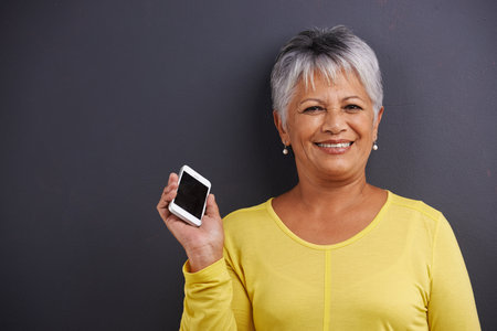 Portrait of a mature woman holding a mobile phone in a studio.