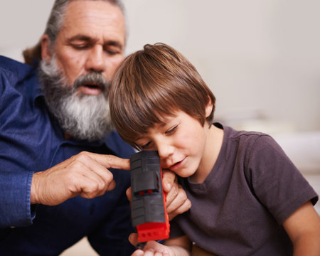 Giving him a detailed history on the railroad. a grandfather showing his grandson a toy train.の素材 [FY310191629788]