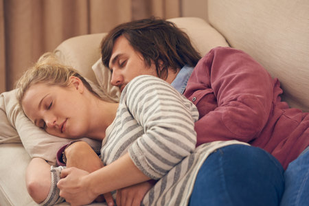 Shes always comfortable in his arms. an affectionate young couple sleeping on the sofa.