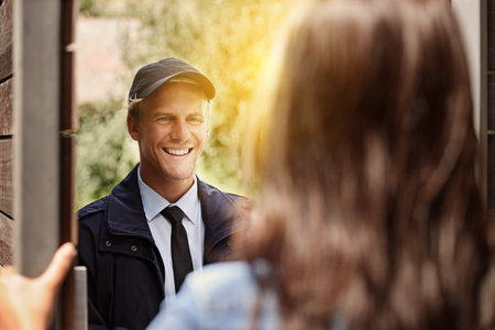 Ive got your delivery. a young man making a delivery to a woman at her home.の写真素材