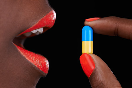Cropped view of an african woman with bright red lips taking a pill.の写真素材