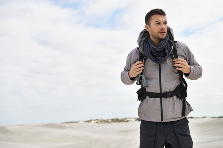 Tackling every kind of terrain. a young male hiker walking along the sand dunes.