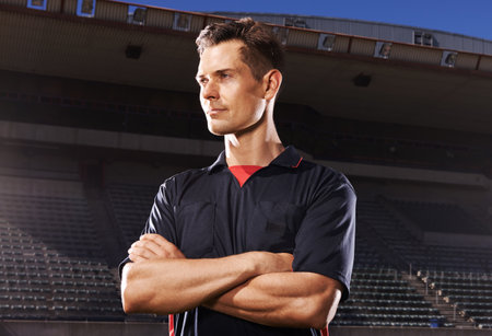 Confident before the game. A young athlete standing in the stadium lights.