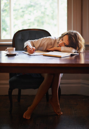 Transferring peace onto the page. an attractive young woman writing in a relaxed environment at home.の写真素材