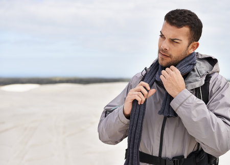 a young male hiker walking along the sand dunes.