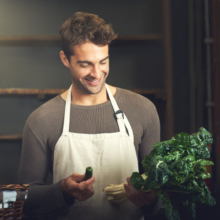 .A young man holding spinach and a green jalapeno.