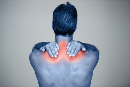 Feeling the aches and pains. Rear view studio shot of a mature man rubbing the highlighted injury on his body.の写真素材