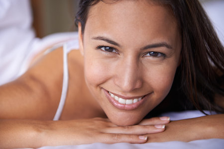 Closeup portrait of a beautiful young woman lying on her bed.の写真素材