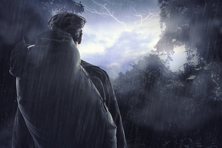 The magnificence of nature. a hiker watching a thunderstorm over a mountain through a clearing in...