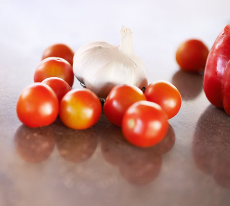 Ready for chopping. A cropped shot of garlic and tomatoes on a kitchen counter.の写真素材