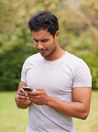 a young man standing outside using a cellphone.の写真素材