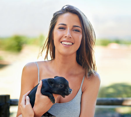 A young woman holding a cute piglet.の写真素材