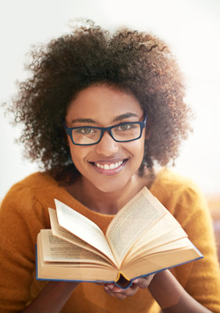 Cropped portrait of a young woman paging through a book.