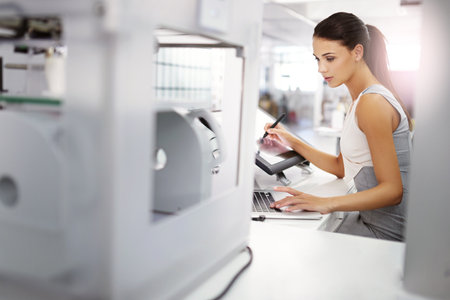 a designer working on a touchscreen computer and a 3d printer.
