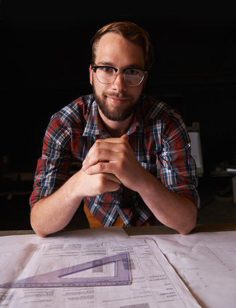 Let the beauty we love become what we do. a young man sitting indoors working on building plans.の写真素材