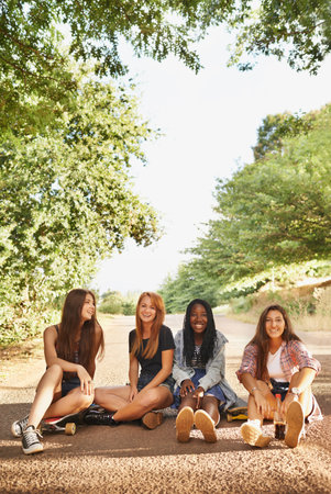 A group of multiracial teens sitting outdoors enjoying each others company.