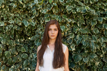 Confidently stepping into adulthood. Portrait of an attractive teenage girl standing in front of a large hedge.の写真素材