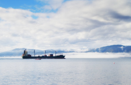 Carrying valuable cargo. A freight ship travelling along the coast line.の写真素材