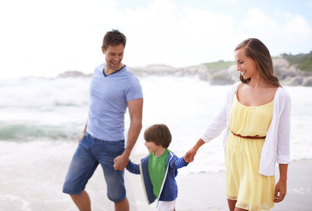 Strolling along the beach. a happy family walking on the beach.の写真素材