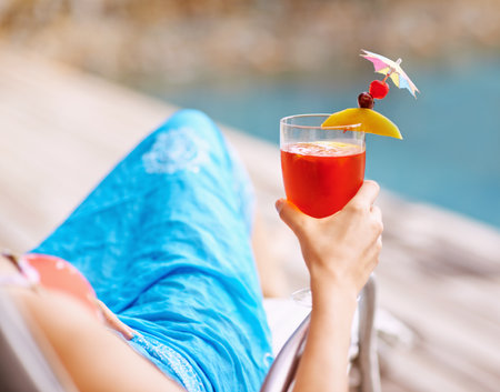 a woman holding a cocktail by the poolside.の写真素材