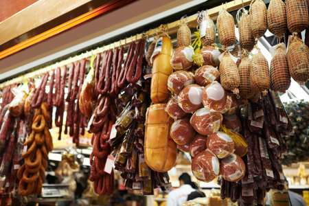 Meat lovers market. dried sausages and salami hanging on hooks at a market stall.の写真素材