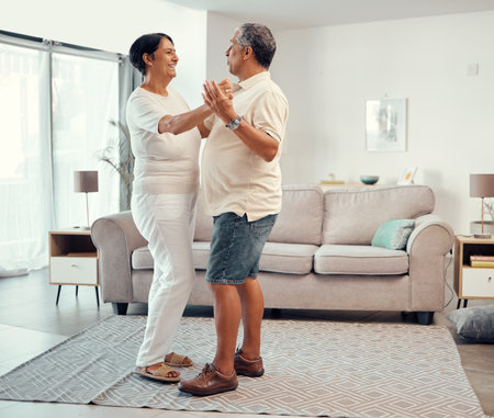 Senior couple dancing in living room home for love, retirement or real estate. Dance together, celebration of marriage and elderly people smile. hug and share life with affection, freedom and careの写真素材
