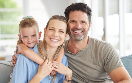 Children, family and love with a girl and her parents on a sofa in the living room of their home...