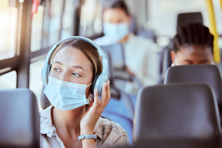 Covid, bus and woman with face mask and headphones listening to podcast on safety compliance, freedom or health risk. Girl city travel or transportation and music for corona virus radio news updateの写真素材