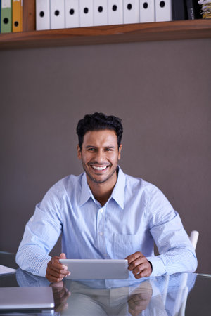 Hes working hard to complete his tasks. a handsome young businessman working at his desk.の写真素材