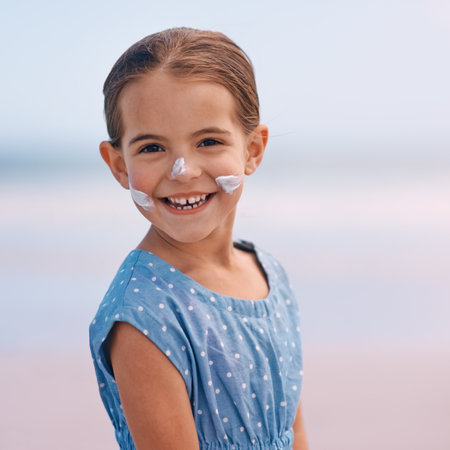 Shes safe with her sunscreen. Portrait of a smiling little girl with suntan lotion on her face.の写真素材